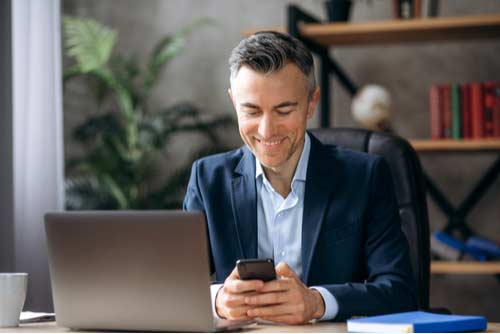 Businessman at desk sending text messages