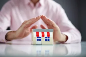 Hands hovering over a model building represent insurance defense.