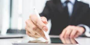Businessperson using stylus to create electronic signature on tablet for legal contract