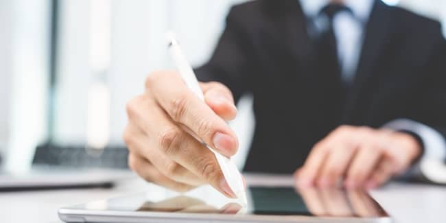 Businessperson using stylus to create electronic signature on tablet for legal contract
