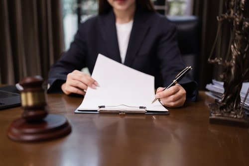 Female lawyer reviwieng legal papers in a breach of contract case for a client at a table with a gavel.